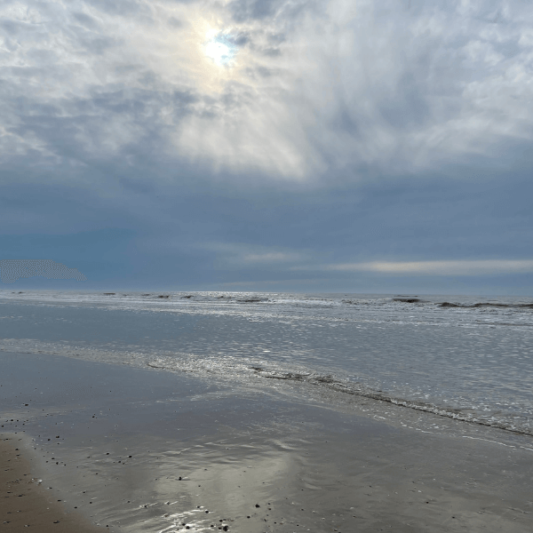 Sonne schaut durch die dichten Wolken am Strand