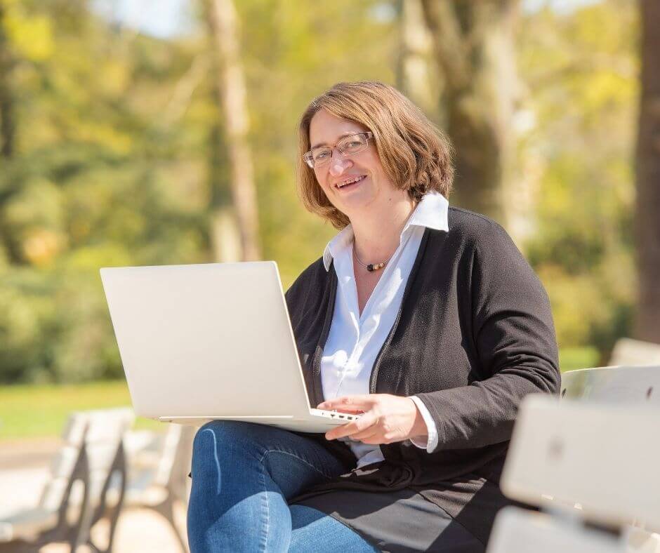 Claudia Kielmann ist draußen an einem Laptop